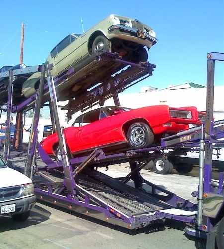 Buys Classic Cars car hauler with red Pontiac GTO and Plymouth Barracuda